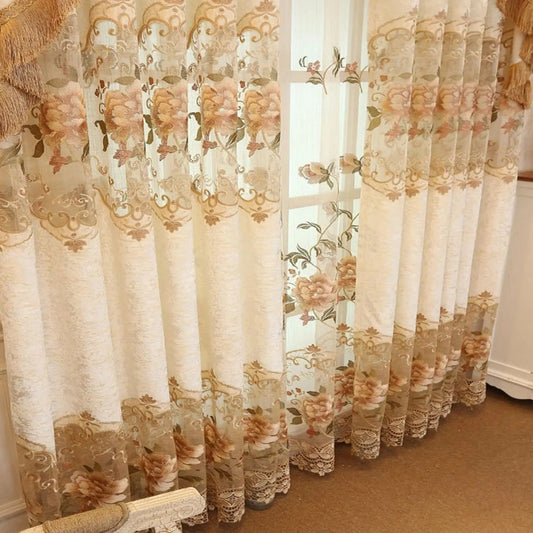 Gros plan sur le voilage vintage beige à motifs floraux et arabesques, avec de la lumière filtrant doucement à travers.