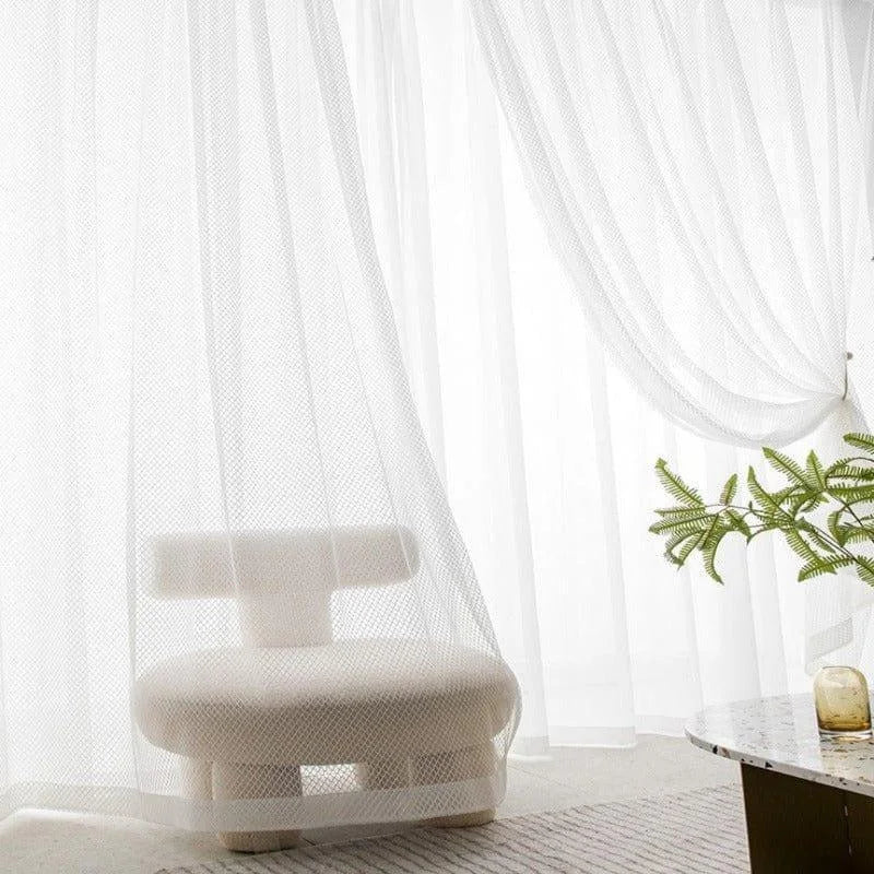 Fauteuil design moderne blanc dans un salon lumineux avec rideaux élégants et plante verte sur une table basse. Ambiance minimaliste et épurée idéale pour un intérieur contemporain et raffiné.