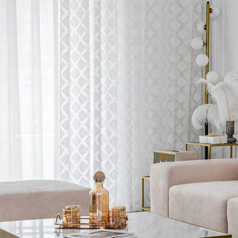 Salon élégant avec rideaux blancs à motifs géométriques, créant une ambiance lumineuse. Canapé moderne couleur beige, table basse en marbre avec objets décoratifs dorés. Parfaite harmonie de design intérieur contemporain.