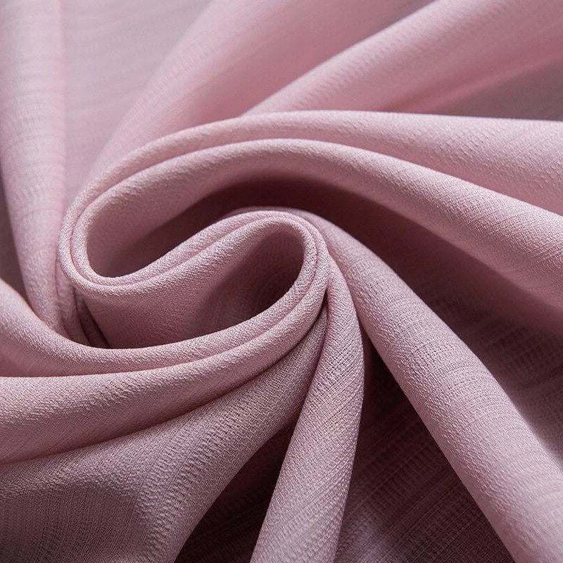 Tissu de couleur rose pastel drapé avec élégance, idéal pour la confection de vêtements délicats et projets de décoration intérieure raffinée.
