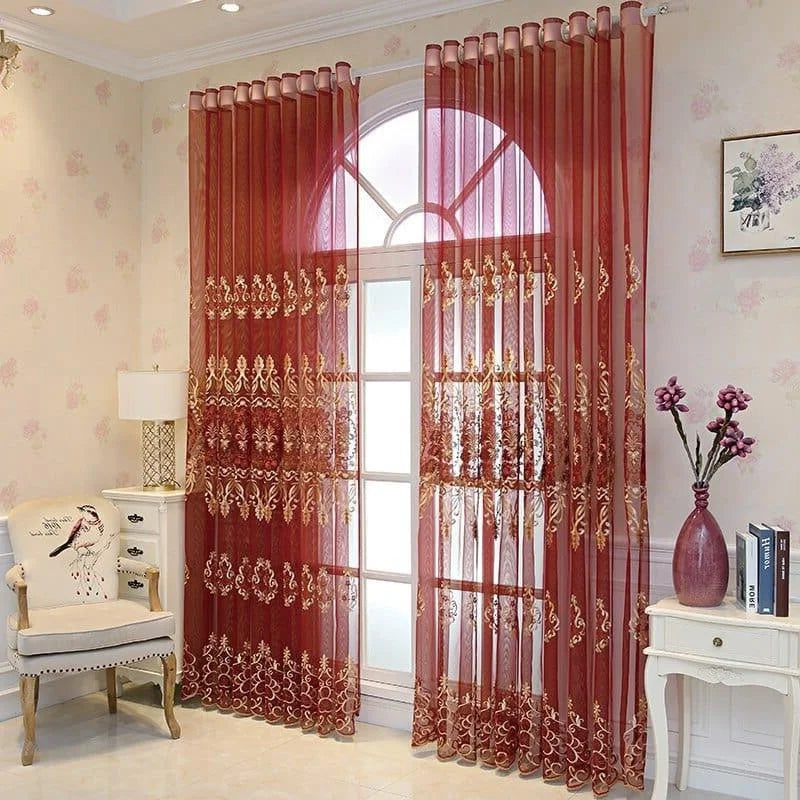 Rideaux élégants translucides couleur bordeaux ornés de motifs dorés, ajoutant une touche sophistiquée à un salon lumineux avec décoration florale et mobilier classique. Parfait pour embellir vos fenêtres avec style et raffinement.