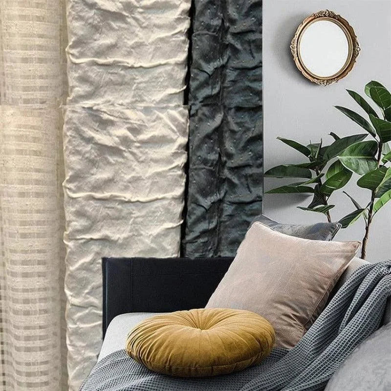 Image montrant un salon moderne avec un assortiment de coussins décoratifs aux couleurs douces, une plante verte ajoutant une touche naturelle, et un miroir rond encadré sur le mur. Les rideaux texturés créent une ambiance élégante et confortable. Parfait pour un espace de détente accueillant.