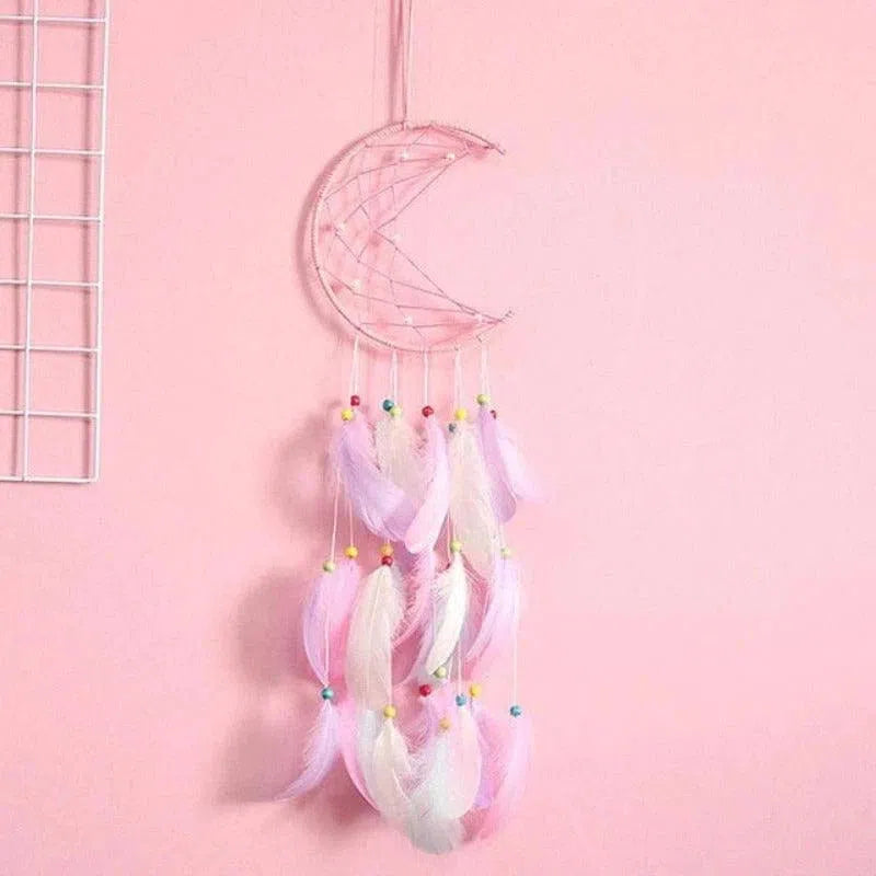 Attrape-rêves en forme de croissant de lune avec plumes et perles colorées, décoration murale tendance pour chambre d'enfant ou chambre à coucher. Ambiance douce et apaisante grâce à ses teintes pastel, idéal pour favoriser des nuits paisibles.