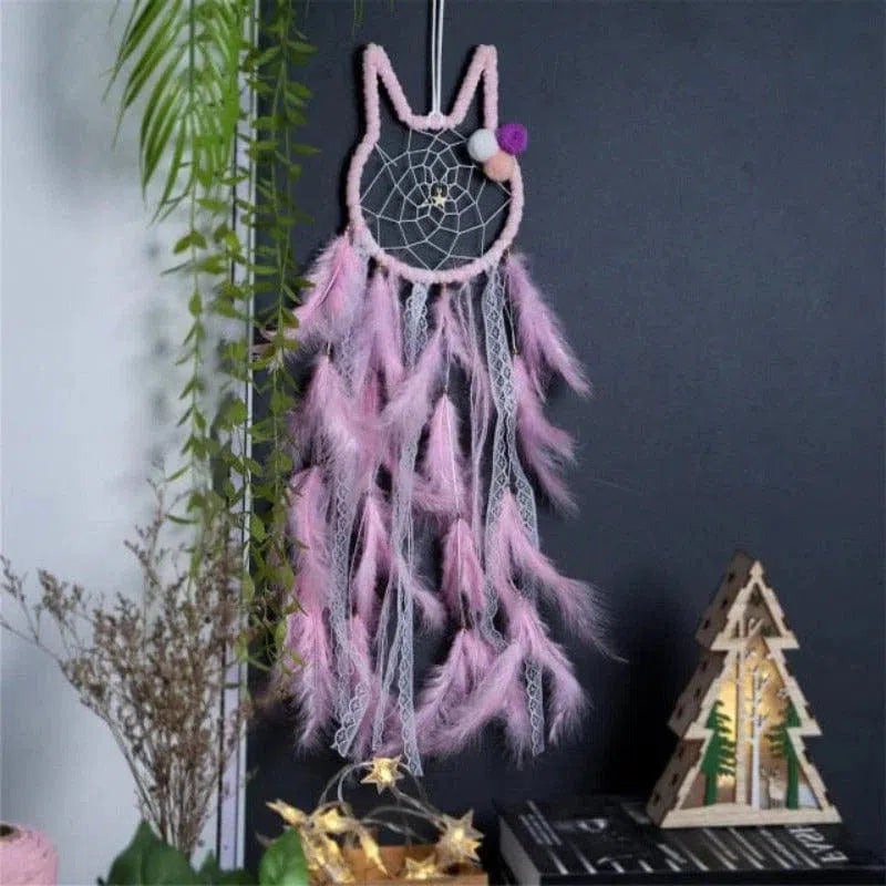 Attrape-rêves décoratif rose en forme de chat pour chambre d'enfant, doté de plumes suspendues. Accessoire idéal pour créer une ambiance apaisante et onirique dans la maison. Parfait pour une décoration murale originale alliant élégance et sérénité.