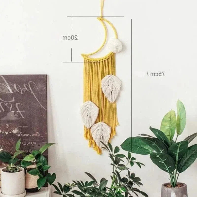 Décoration murale bohème avec motifs en forme de feuilles, suspendue dans un intérieur moderne et agrémentée de plantes vertes. Parfait pour ajouter une touche de naturel et de chaleur à votre décoration d'intérieur. Dimensions indiquées : 20 cm de large et 75 cm de long.