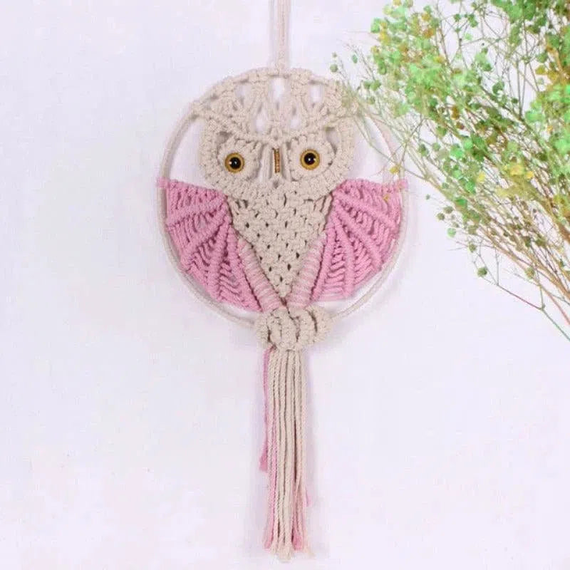 Suspension murale hibou en macramé avec détails roses, parfait pour une décoration bohème et naturelle dans votre intérieur. Fait main, ce capteur de rêves hibou ajoute une touche originale et charmante à votre espace de vie. Idéal pour une chambre d'enfant ou un salon à l'ambiance apaisante. Accessoire déco artisanal et tendance.