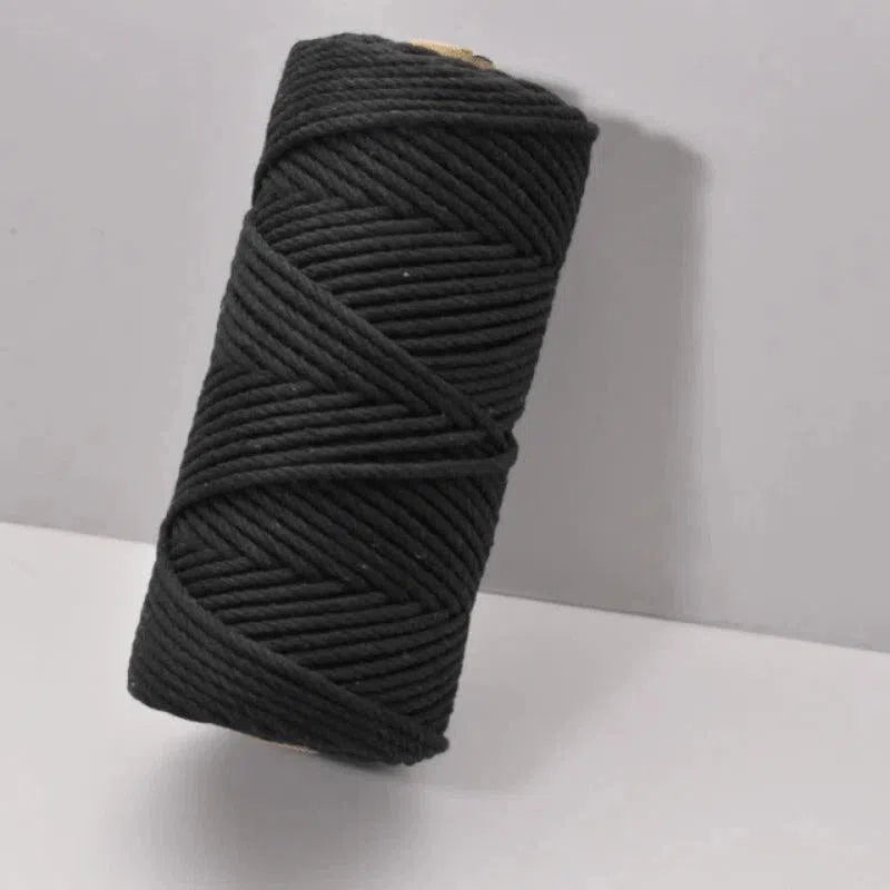 Bobine de fil enroulé, couleur sombre, posée sur une surface claire, idéale pour projets créatifs et décoratifs, parfaite pour le bricolage et les activités manuelles.