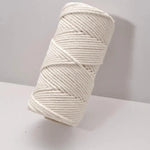 Bobine de fil blanc épais sur une surface blanche, idéale pour les projets de macramé, le jardinage, ou les travaux manuels créatifs. Accessoire essentiel pour les passionnés d'artisanat ou de décoration intérieure fait main.