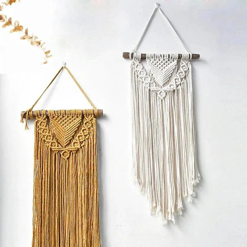 Deux tentures murales en macramé, une dorée et une blanche, suspendues sur un mur blanc. Design bohème chic parfait pour la décoration intérieure. Idéales pour ajouter une touche artisanale à un salon ou une chambre. Accessoires décoratifs tendance et élégants.