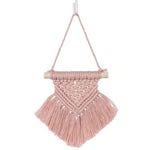 Suspension murale décorative rose en macramé avec franges, idéale pour ajouter une touche boho à votre intérieur. Parfaite pour embellir une chambre, un salon ou un bureau. Accessoire artisanal élégant accroché à un bâton en bois design.