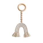 Hochet bébé design en forme d'arc-en-ciel avec anneau et perles. Jouet d'éveil idéal pour les nouveau-nés, favorisant la stimulation sensorielle et la motricité fine. Accessoire décoratif sobre et élégant pour chambre d'enfant. Cadeau parfait pour une naissance ou un baptême.