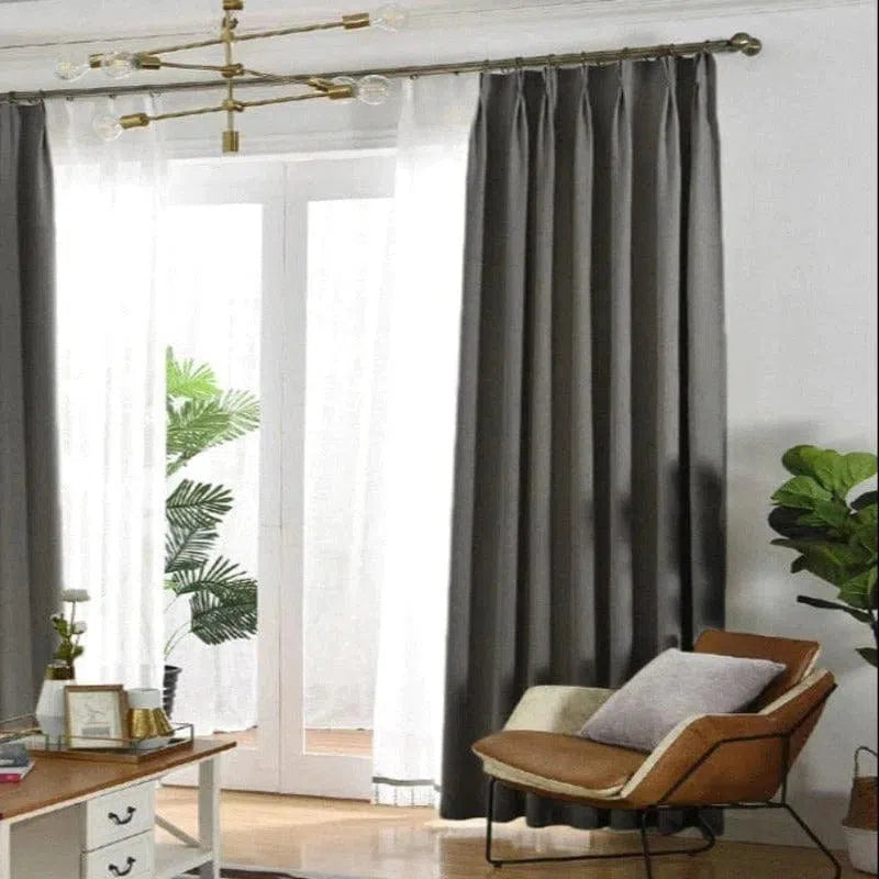 Rideaux élégants de couleur sombre encadrant une porte-fenêtre, apportant une touche moderne et chaleureuse au salon. Décoration intérieure soignée avec plantes vertes en arrière-plan et mobilier contemporain, créant une ambiance harmonieuse idéale pour un espace de vie confortable. Éclairage naturel traversant la pièce, soulignant la sophistication du décor.