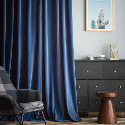 Rideau bleu élégant dans un salon moderne avec un fauteuil à motifs et une commode noire. Décoration intérieure raffinée, ambiance chaleureuse et sophistiquée, idéale pour ajouter une touche de style à votre espace de vie.