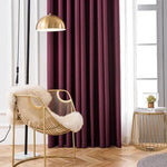 Fauteuil design doré avec coussin moelleux dans un salon moderne, éclairé par une lampe suspendue. Rideau prune et table d'appoint avec plante d'intérieur. Idée déco élégante pour un intérieur chic et chaleureux.