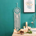Attrape-rêves mural élégant suspendu devant un mur turquoise dans une ambiance intérieure chaleureuse. Parfait pour ajouter une touche de décoration bohème à votre maison. Idéal pour le salon, la chambre ou un espace zen. Accompagnez-le de bougies et de petits objets déco pour un effet apaisant et harmonieux.