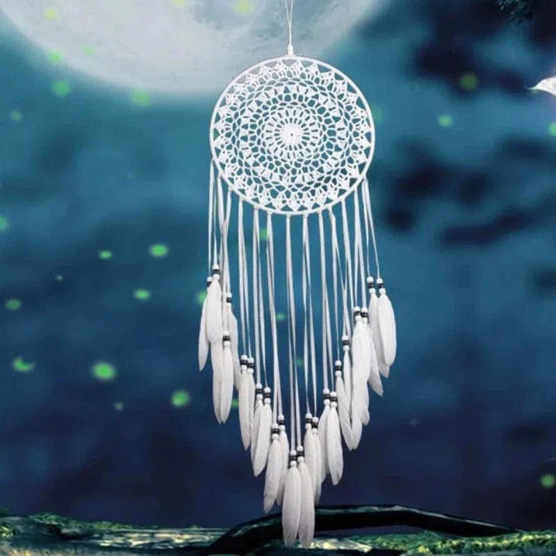 Attrape-rêves artisanal élégant suspendu sous un ciel nocturne étoilé. Ce capteur de rêves blanc est orné de plumes délicates, parfait pour apporter une touche de sérénité et d'élégance à votre décoration intérieure. Idéal pour apaiser vos nuits et ajouter une esthétique bohème à votre chambre.
