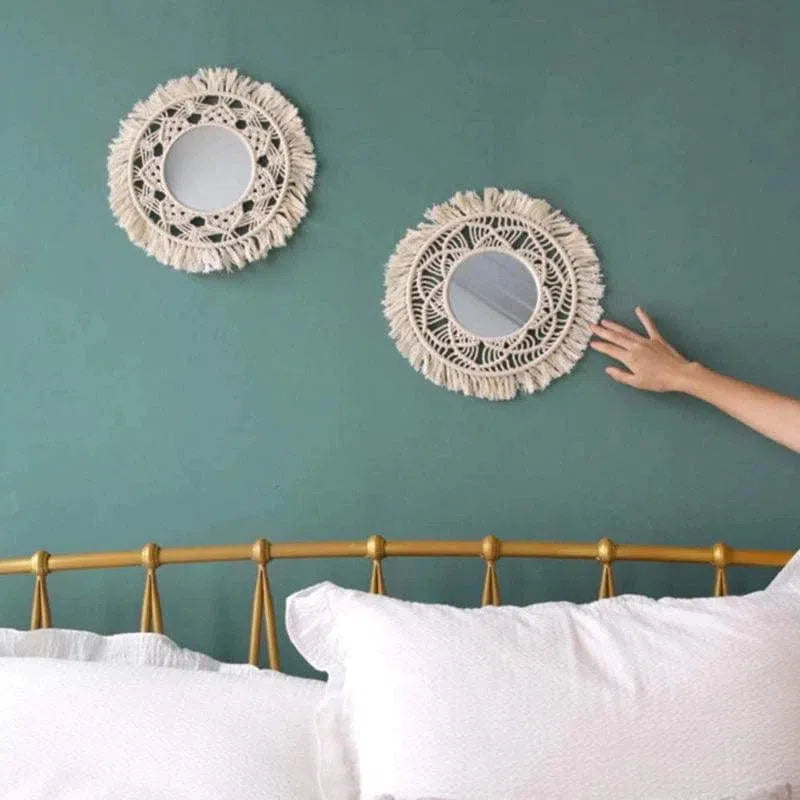 Deux miroirs décoratifs ronds accrochés sur un mur vert dans une chambre élégante. Touche bohème et moderne à la fois, ces pièces ajoutent une dimension artistique au décor. Une main ajuste le positionnement des miroirs au-dessus d'un lit avec une tête de lit dorée. Ambiance reposante et stylée grâce à un design original et harmonieux.