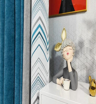 Décoration d'intérieur moderne avec rideaux élégants en nuances de bleu et motifs géométriques. Une statuette artistique ajoute une touche de personnalité, tandis qu'un élément décoratif doré apporte une touche de luxe. Une parfaite harmonie pour un salon contemporain et chic.