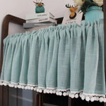 Rideau court bleu turquoise avec pompons blancs pour décoration intérieure, parfait pour ajouter une touche d'élégance à votre pièce, se marie bien avec un mobilier de style moderne et offre une ambiance rafraîchissante. Idéal pour habiller une étagère ou une fenêtre.