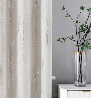 Rideau décoratif moderne avec motif ondulé argenté, idéal pour un salon élégant. Le rideau est présenté à côté d'un vase cylindrique transparent avec des branches de feuillage, ajoutant une touche zen et naturelle à l'intérieur. Parfait pour créer une atmosphère apaisante et sophistiquée dans votre espace de vie.