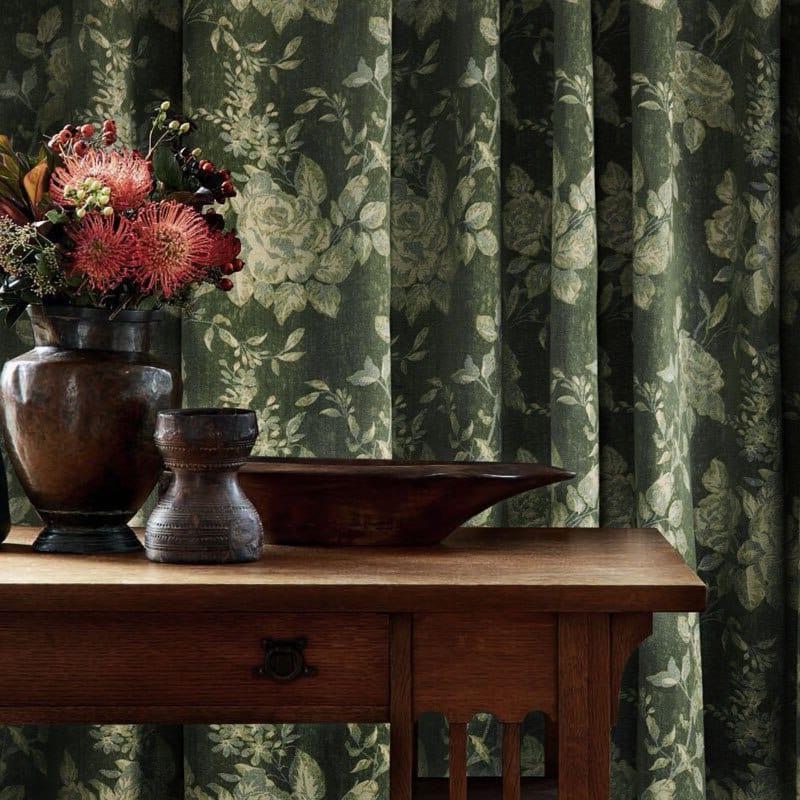 Rideau élégant à motifs floraux verts, ajoutant une touche de sophistication et de charme à votre intérieur, vu derrière une table en bois avec des vases décoratifs. Idéal pour apporter une ambiance naturelle et apaisante à votre salon ou chambre.