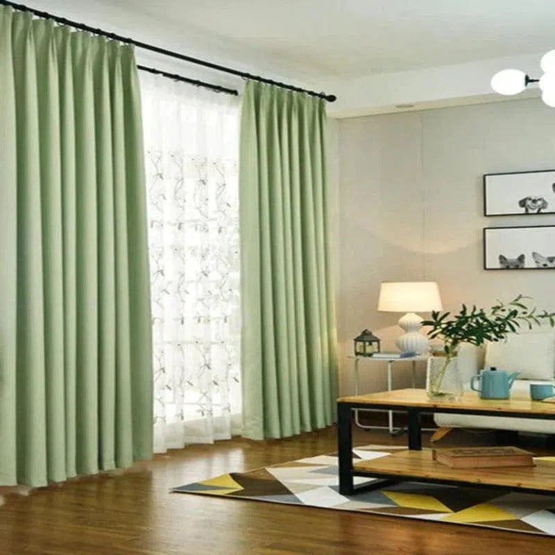 Rideaux verts pour salon moderne, décoration intérieure élégante avec table basse en bois, lampe et tableau mural, ambiance lumineuse et accueillante parfaite pour un espace de détente et de confort.