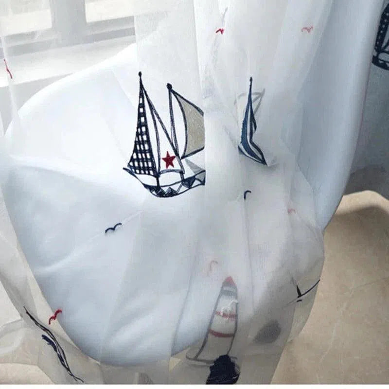 Voile de rideau blanc avec motifs nautiques, incluant des voiliers brodés et des étoiles rouges. Idéal pour une décoration intérieure inspirée par la mer, apportant une touche maritime et lumineuse à votre pièce. Parfait pour les chambres d'enfants ou les salons à thème marin, offrant une ambiance légère et apaisante.