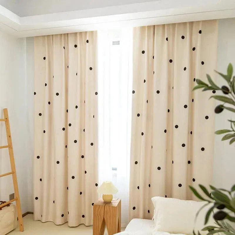 Rideaux élégants à motif de pois noirs, ajoutant une touche moderne et stylée à une chambre lumineuse. Parfait pour améliorer la décoration intérieure avec une ambiance chaleureuse et légère. Accessoires incluant une échelle en bois et une petite table de chevet avec une lampe, complétant harmonieusement l'ensemble.