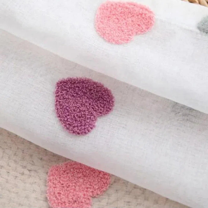 Image d'un tissu blanc décoré de motifs en forme de cœur roses et violets, parfait pour ajouter une touche de tendresse à votre décoration intérieure ou à vos projets de couture. Idéal pour créer des articles personnalisés ou des cadeaux uniques.