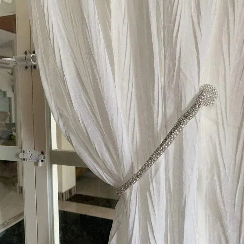 Attache-rideau élégante sur rideau blanc dans un intérieur moderne. Accessoire de décoration pratique et raffiné pour une touche de sophistication à vos fenêtres. Idéal pour usage domestique, renforce l'esthétique de votre salon ou chambre.