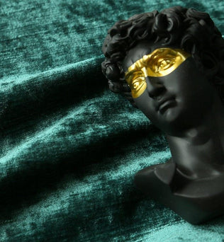 Buste décoratif noir avec masque doré, posé sur un fond texturé vert. Accessoire d'art unique pour la décoration intérieure, ajoutant une touche moderne et élégante à tout espace de vie. Idéal pour les amateurs de design contemporain cherchant à enrichir leur environnement avec une pièce originale et artistique.