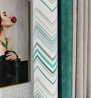 Rideaux modernes aux motifs géométriques, avec un design élégant en chevron, combinant des teintes de turquoise, gris et vert. Parfait pour ajouter une touche artistique à votre intérieur, ces rideaux sont présentés à côté d'une œuvre d'art vibrante, créant un contraste chic et raffiné dans votre salon. Idéal pour ceux qui cherchent à harmoniser décoration artistique et fonctionnalité dans leur espace de vie.