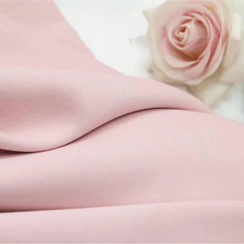 Tissu rose poudré élégant, idéal pour des créations de couture raffinées, avec une rose assortie ajoutant une touche de romantisme. Parfait pour des projets de décoration intérieure ou de mode, apportant douceur et sophistication.
