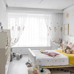 Chambre d'enfant lumineuse et moderne avec lit confortable décoré de coussins colorés. Rideaux à motifs ludiques ajoutant une touche de fantaisie. Meubles de rangement pratiques et espace de jeu avec jouets harmonieux. Ambiance douce et accueillante pour un espace de rêve.