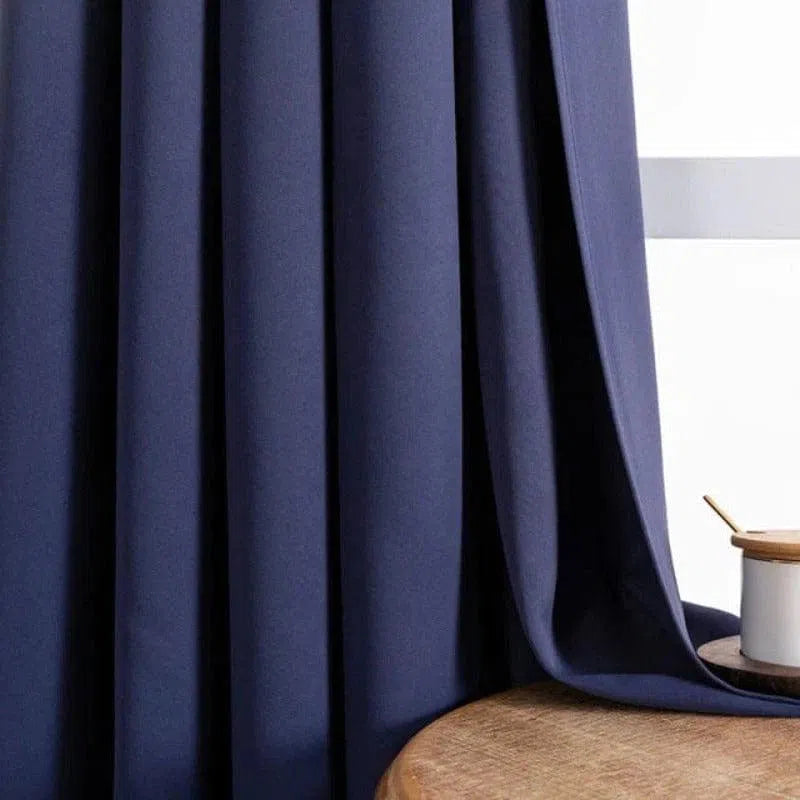 Rideau élégant bleu sombre, apportant une touche moderne et chic à tout intérieur, suspendu près d'une table en bois pour une ambiance chaleureuse et apaisante.