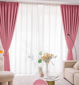 Rideaux élégants de couleur rose installés dans un salon moderne, offrant une ambiance lumineuse et chaleureuse grâce à la combinaison de voilages blancs. Complétant le décor, un canapé confortable et une table basse ornée de fleurs jaunes ajoutent une touche de sophistication et de confort à l'intérieur. Parfait pour créer un espace accueillant et stylé.