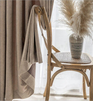 Voilage élégant beige pour intérieur moderne, accroché à une chaise en bois, apportant une ambiance chaleureuse et apaisante à votre décoration d'intérieur. Complété par un vase décoratif avec des pampas, ce rideau ajoute une touche de sophistication à tout espace domestique. Idéal pour améliorer l'esthétique d'un salon ou d'une chambre.