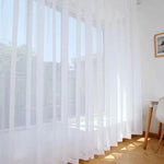Rideau blanc transparent suspendu dans une pièce lumineuse, laissant entrer la lumière naturelle tout en préservant l'intimité. Design élégant et minimaliste, idéal pour salon moderne ou chambre à coucher. Ajustement parfait pour des fenêtres larges, ajoutant une touche de sophistication à la décoration intérieure.