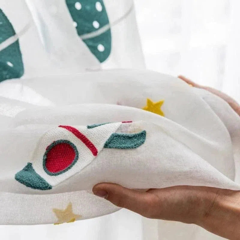 Rideau pour chambre d'enfant avec motif de fusée et étoiles, idéal pour une décoration ludique sur le thème de l'espace. Accessoire parfait pour ajouter une touche de fantaisie à la pièce tout en filtrant délicatement la lumière. Produit pour éveiller l'imagination des petits explorateurs.
