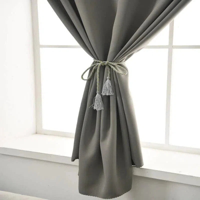 Rideau moderne gris pour décoration intérieure, ajoute élégance à toute pièce, idéal pour salon et chambre, noué avec embrasse à franges pour un style raffiné.