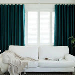 Rideaux verts élégants habillant une fenêtre dans un salon moderne, ajoutant une touche de couleur et de sophistication à l'intérieur. Canapé blanc confortable en premier plan, créant un contraste harmonieux avec les rideaux. Ambiance lumineuse et accueillante.