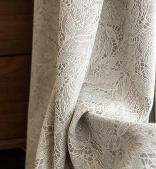 Rideau élégant en dentelle beige avec motif floral, idéal pour apporter une touche de sophistication et d'intimité à votre salon ou chambre. Tissu léger offrant une diffusion subtile de la lumière naturelle.