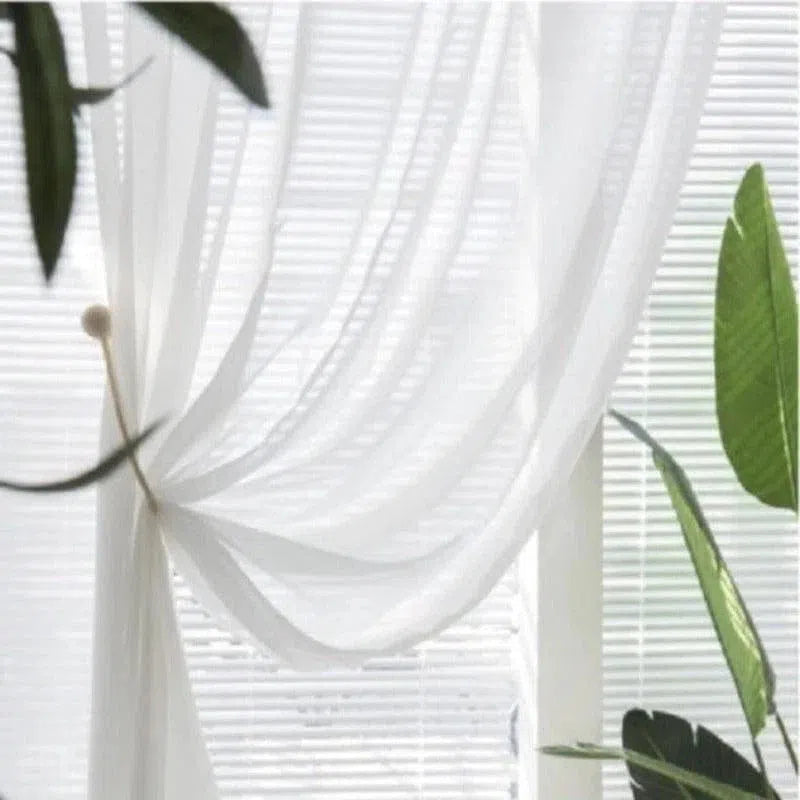 Rideau blanc élégant laissant filtrer la lumière, idéal pour une décoration intérieure lumineuse. Parfait pour ajouter une touche de légèreté au salon, tout en préservant l'intimité. Parfait pour les fenêtres de toute taille, avec un design intemporel et raffiné.