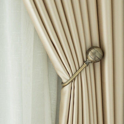 Rideau élégant beige attaché par un embrasse métallique, offrant une décoration raffinée et une lumière tamisée dans la pièce. Design moderne et chic parfait pour une ambiance cosy et contemporaine. Accessoire idéal pour ajouter une touche de sophistication à votre intérieur.