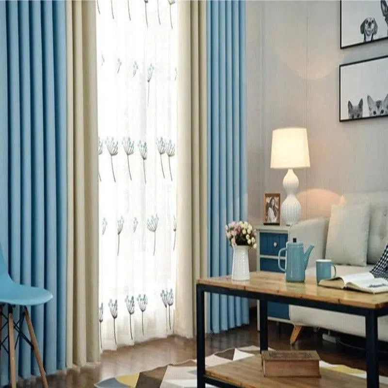 Rideaux modernes bleu clair et beige dans un salon élégant avec une table en bois et métal, chaise minimaliste, canapé confortable et lumière douce d'une lampe. Les rideaux filtrent la lumière tout en ajoutant une touche de fraîcheur et d'élégance à la pièce. Parfait pour un aménagement intérieur contemporain.