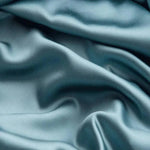 Image de tissu luxueux bleu avec des plis doux, parfait pour la confection de vêtements élégants ou d'articles de décoration sophistiqués. Ce textile capture la lumière d'une manière élégante, ajoutant une touche de finesse et de raffinement à tout design. Idéal pour les créateurs cherchant à réaliser des œuvres originales et tendances.