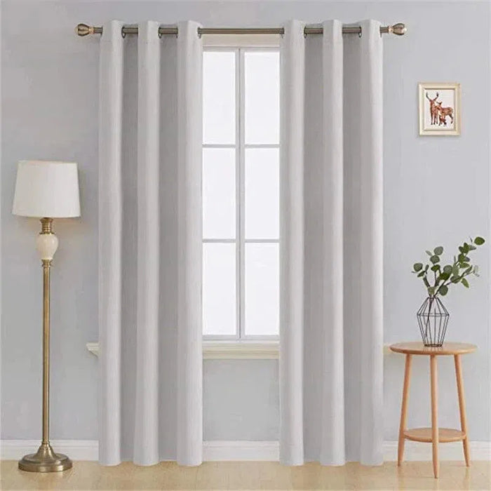 Rideau blanc élégant pour salon, avec œillets métalliques pour installation facile, combiné avec une décoration intérieure moderne comprenant une lampe sur pied et une petite table avec une plante. Idéal pour illuminer et embellir votre espace de vie. Parfait pour créer une atmosphère paisible et raffinée.