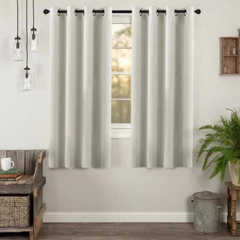 Rideau occultant moderne de couleur beige clair, idéal pour un salon élégant. Ce rideau en tissu épais est suspendu à une tringle noire à œillets, ajoutant une touche contemporaine à votre décoration intérieure. Parfait pour bloquer la lumière et offrir de l'intimité dans votre pièce. Accessoire décoratif pour les maisons modernes, ce rideau est à la fois fonctionnel et esthétique.