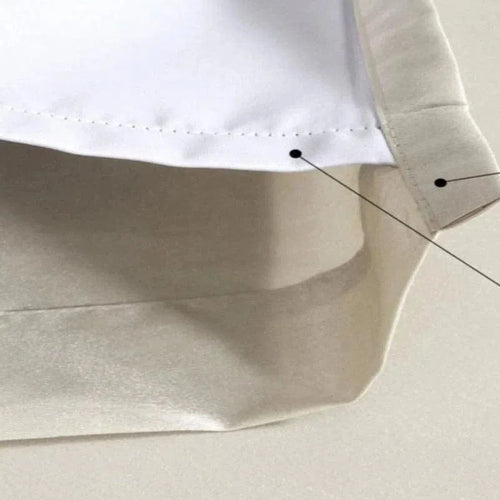 Gros plan sur un rideau d'intérieur blanc et beige, mettant en évidence les détails de couture et les finitions soignées, parfait pour ajouter une touche moderne et élégante à votre salon ou chambre.