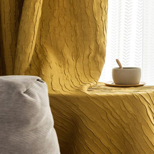 Rideau jaune texturé apportant élégance et chaleur à votre intérieur, accompagné d'un canapé gris et d'un mug sur une soucoupe, idéal pour un espace cosy et moderne. Parfait pour sublimer votre salon ou votre chambre.